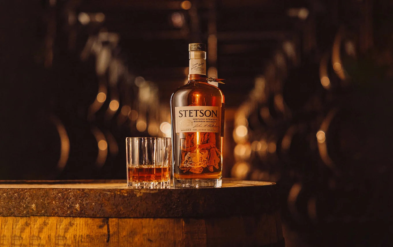 Stetson Bourbon bottle and glass on a barrel